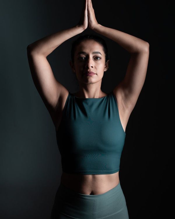 Woman in a calm, focused yoga pose against a dark background.
